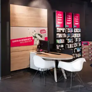 Beratungsbereich im Elektronikmarkt mit Tisch, Stühlen und Handy-Zubehörwand